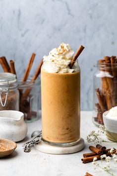 there is a cup with whipped cream and cinnamon sticks in it next to some spices