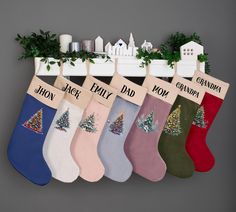 five christmas stockings hanging on a shelf with the names of their favorite holiday trees and houses