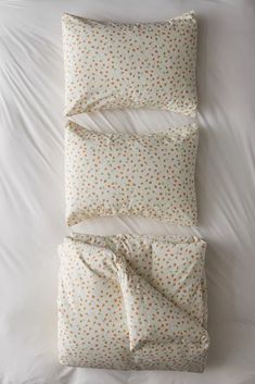 an unmade bed with white sheets and polka dots