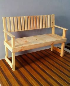 a wooden bench sitting on top of a hard wood floor next to a blue wall