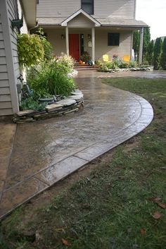 a house that has a driveway in front of it and some plants on the side