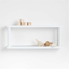 two white shelves with stuffed animals on each shelf and wooden blocks in the middle, against a white wall