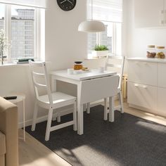 a white table with two chairs and a clock on the wall in a kitchen area