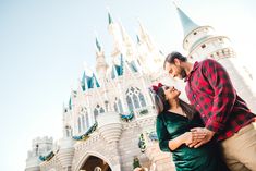 a man and woman standing in front of a castle