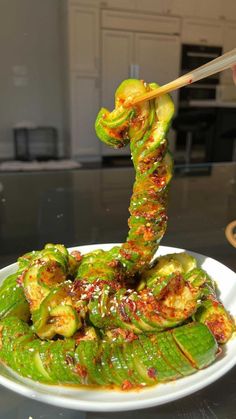 someone is holding chopsticks above a plate of food with green vegetables on it