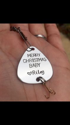 a hand holding a metal christmas ornament that says merry christmas baby