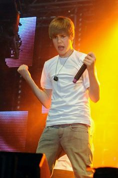 a young man standing on top of a stage holding a microphone in his right hand