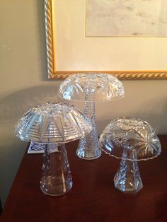 three clear glass dishes sitting on top of a wooden table next to a framed painting