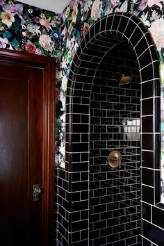 a black and white tiled shower with flowers on the wall next to it, along with a wooden door