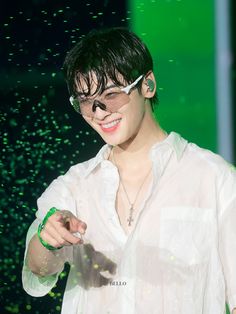 a man in white shirt and glasses holding a green object up to his face while standing on stage