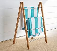 a towel rack with two towels hanging on it's sides and one folded up