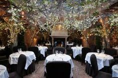 a restaurant with tables and chairs covered in white tablecloths, surrounded by greenery