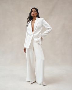 a woman in a white suit posing for the camera with her hands on her hips