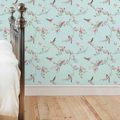 a bed room with a wooden floor and a wall papered with birds on it