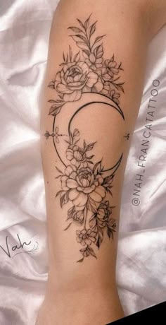 a woman's leg with flowers and a crescent tattoo on it