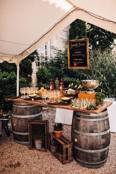 a table with wine glasses and bottles on it under a tent in the middle of a gravel area