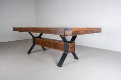 a wooden table with black metal legs in an empty room