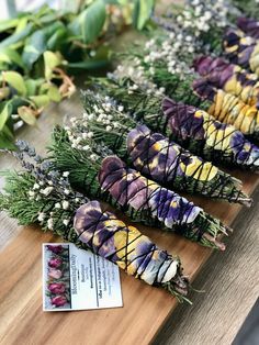 flowers are laid out on a wooden table with some tags in front of the flowers