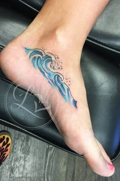 a woman's foot with a wave tattoo on it