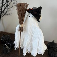 a white ghost with a black hat and broom sitting on top of a wooden table