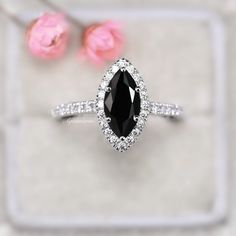 a black and white diamond engagement ring with pink flowers in the background