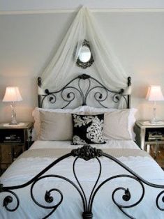 a bed with white sheets and pillows in a bedroom next to two nightstands on either side of the bed