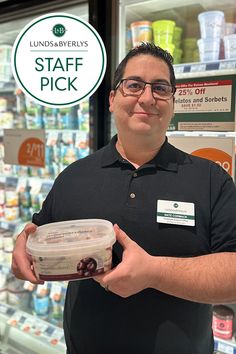 a man holding a container of food in front of a store display with the words staff pick on it