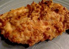 two pieces of fried chicken on a plate with sauce and cheese toppings, ready to be eaten