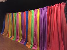 there are many different colored ribbons hanging on the wall in front of a black backdrop