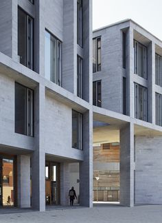 two people walking in front of an apartment building with multiple balconies on each floor