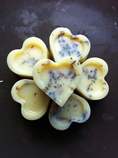 four heart shaped candles sitting on top of a black surface with one candle in the shape of a flower