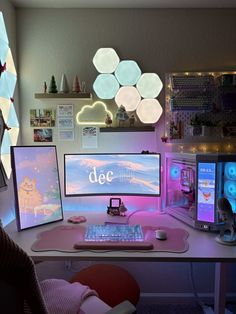 a desk with three computer monitors on top of it and lights hanging from the ceiling