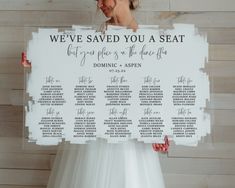 a woman holding up a seating chart for a wedding