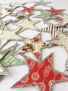 an assortment of christmas ornaments are arranged on a white tablecloth with red, green and silver stars