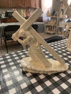 a statue of jesus carrying the cross on a table in a room with black and white checkered tables