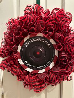 a red wreath with a camera on it that says santa claus cup can be found for christmas