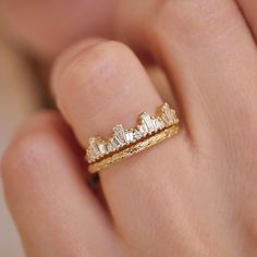 a woman's hand holding a gold ring with three diamonds on top of it