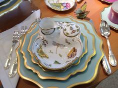 the table is set with dishes, silverware and other decorative items including cups and saucers