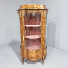 an antique display cabinet with glass doors and gold trimmings on the top shelf