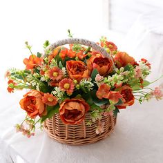 a basket filled with lots of orange flowers on top of a white table covered in cloth