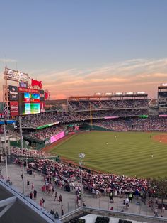 a baseball stadium filled with lots of people watching the game at sunset or sunrise time