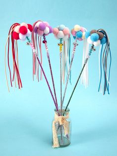 a vase filled with different colored beads and tassels on top of a blue background