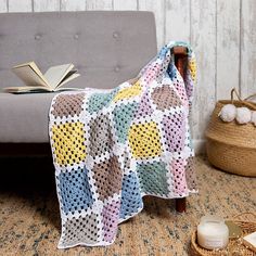 a crocheted blanket sitting on top of a couch next to an open book