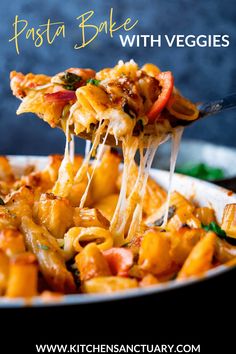 a fork full of pasta being lifted from a skillet with cheese and vegetables on it