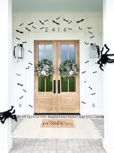 the front door is decorated with bats and wreaths