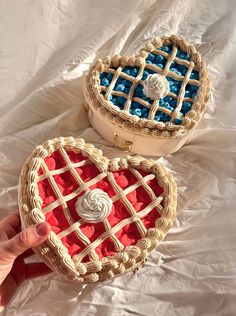 two heart shaped cakes sitting on top of a white cloth covered table next to each other