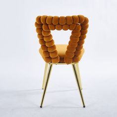 an orange chair with gold legs on a white background in the shape of a heart