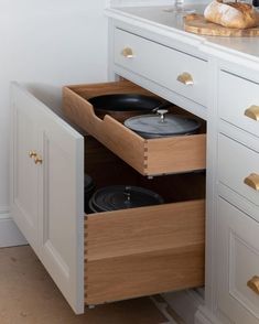 an open drawer in a kitchen with pots and pans on the bottom shelf next to it