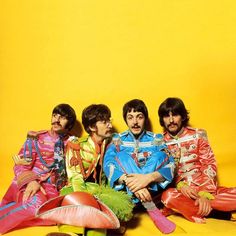 the beatles posing for a photo in front of a yellow background