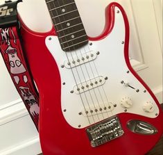 a red and white guitar sitting on top of a wooden floor